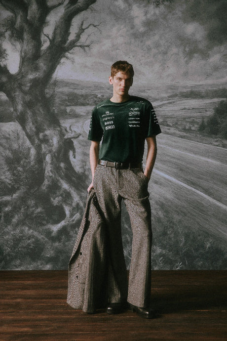 Green Aston Martin shirt worn with pants by seated model.