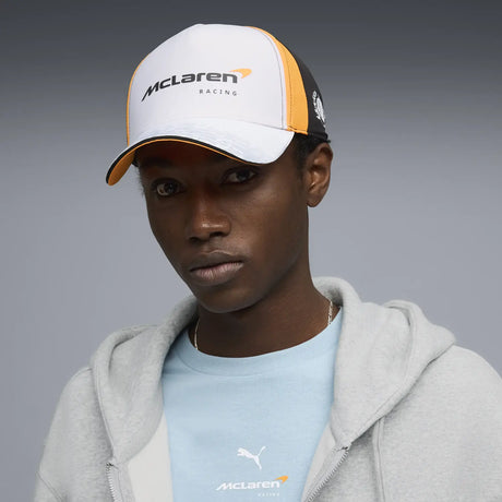 Person wearing McLaren cap white base with orange and black accents
